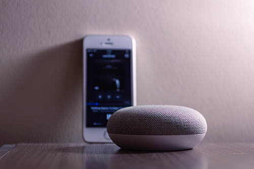objet connecté rond avec un smartphone en arrière-plan
